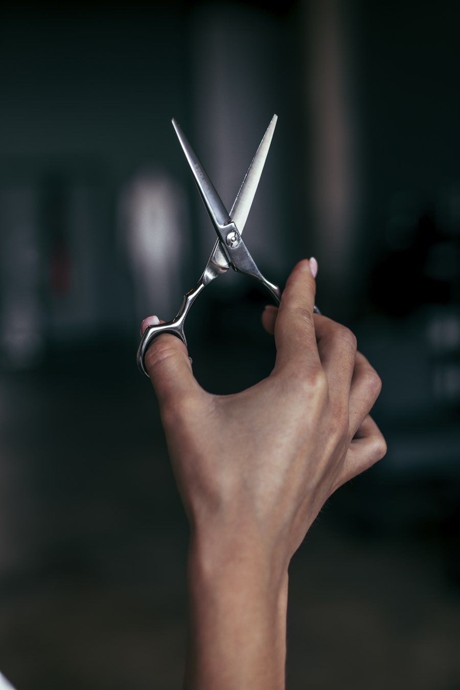 A hand holding open a pair of hairdressing scissors, ready to cut