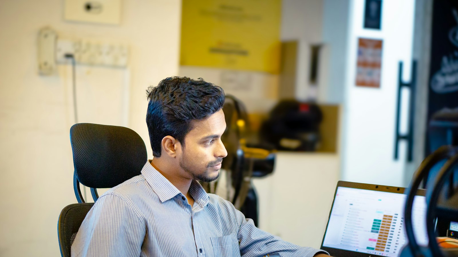 A person working at a laptop in a bright office.